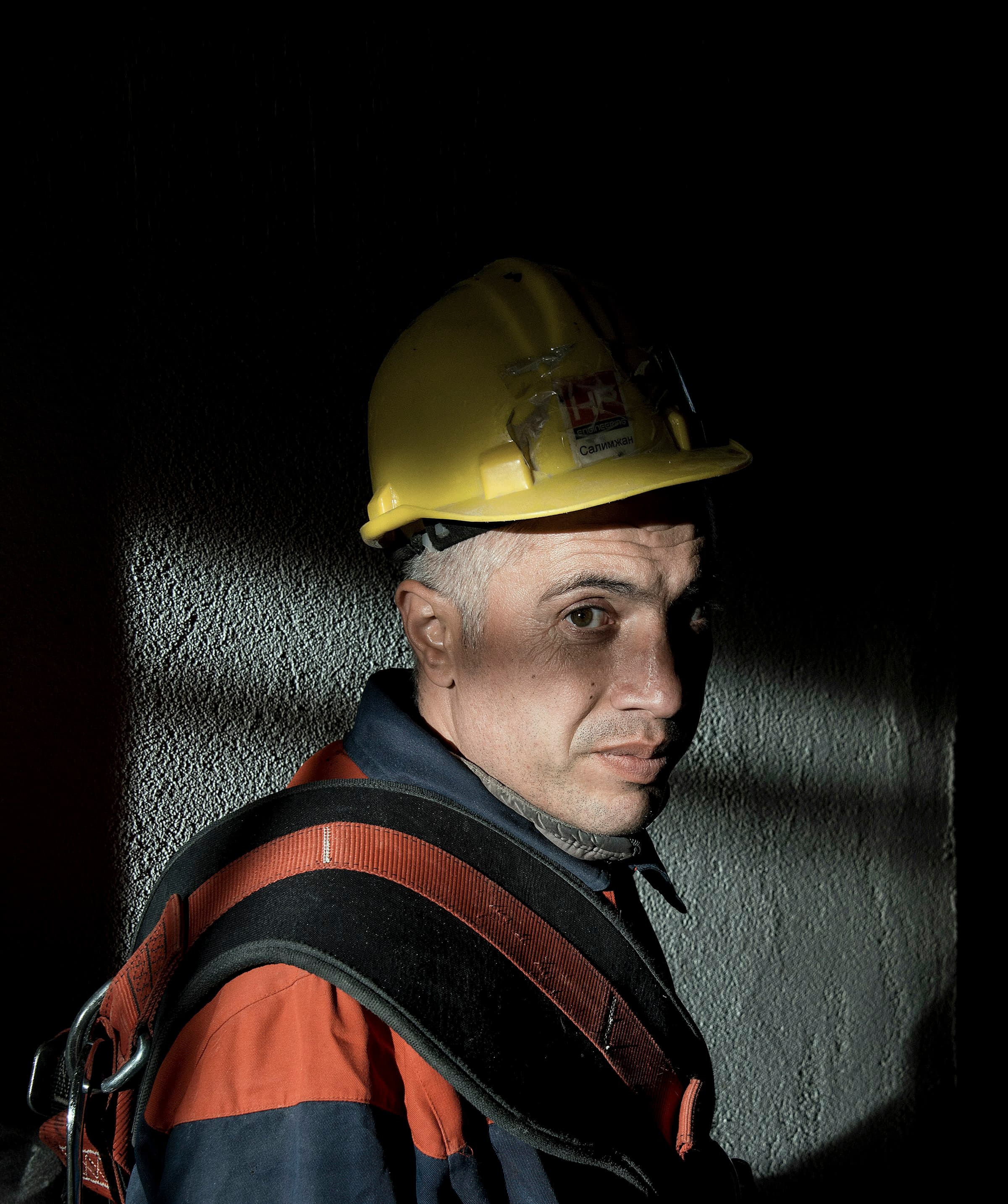 Construction worker in a hard hat lit by a single dramatic shaft of light